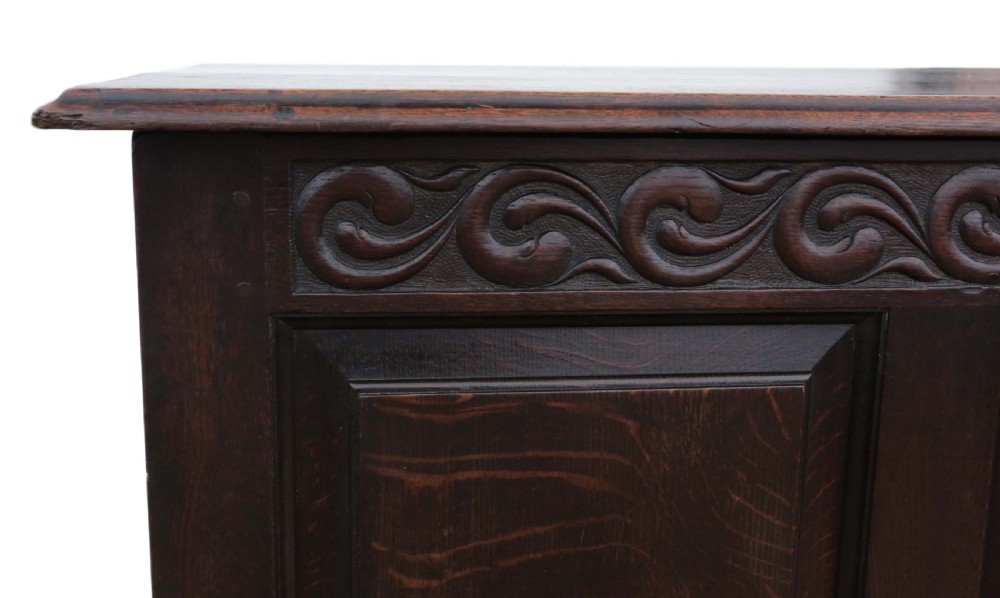 A dark oak Georgian mule chest featuring a carved wave frieze, three fielded front panels, two base drawers with brass handles, and square feet. View IX