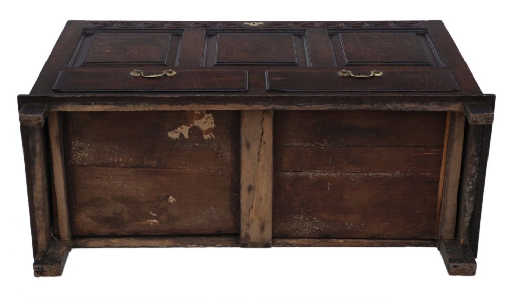 A dark oak Georgian mule chest featuring a carved wave frieze, three fielded front panels, two base drawers with brass handles, and square feet. View XII