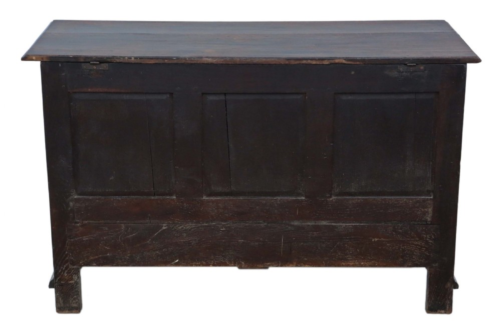 A dark oak Georgian mule chest featuring a carved wave frieze, three fielded front panels, two base drawers with brass handles, and square feet. View XIII