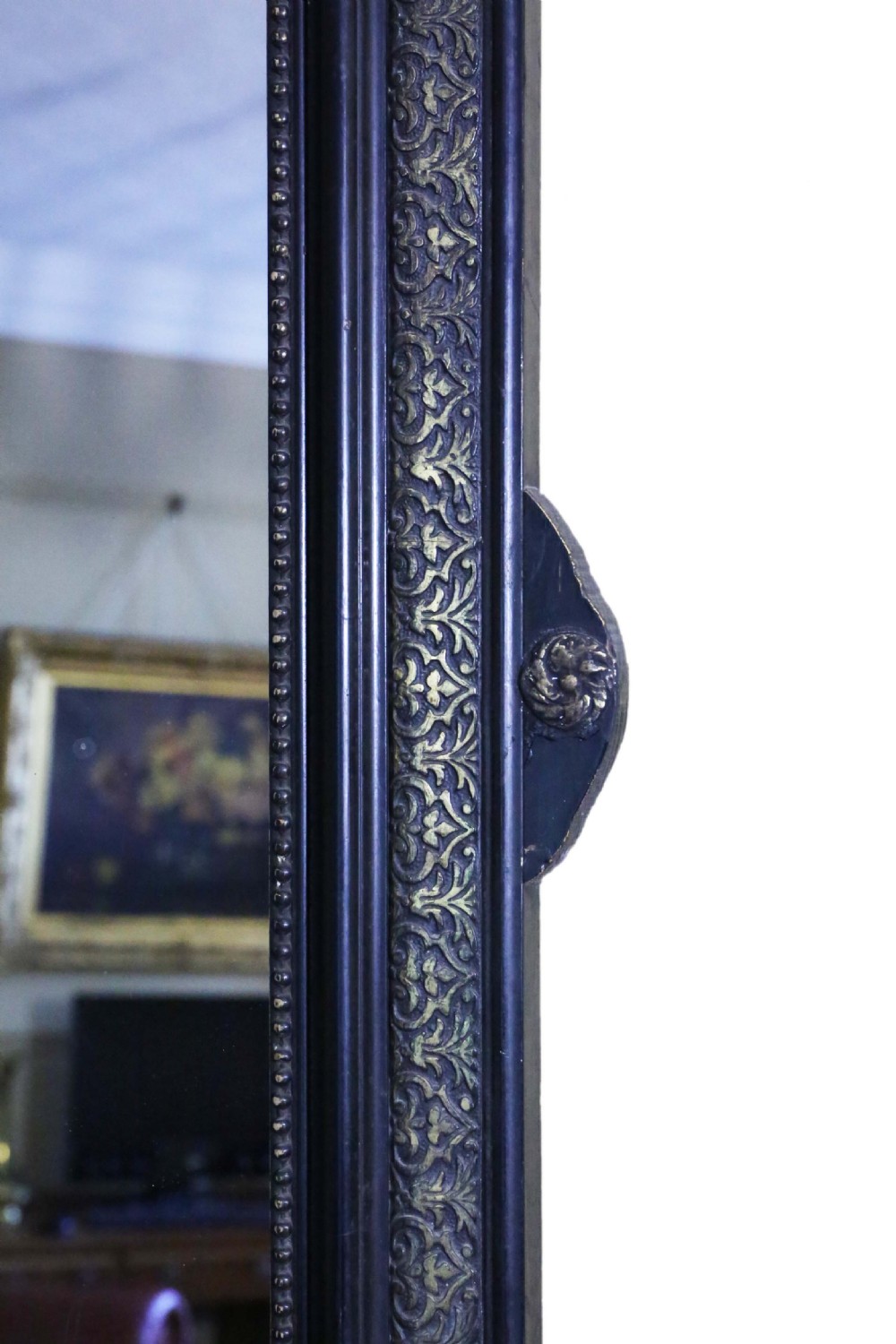 A large rectangular 19th-century ebonised wood overmantel mirror featuring incised gilded borders and a central carved urn pediment flanked by foliate scrollwork. View IV