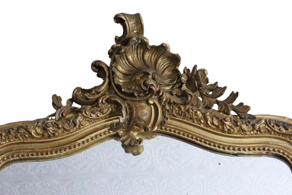 A tall 19th-century arched giltwood overmantel mirror featuring an ornate carved shell crest and decorative moulded frame. View II