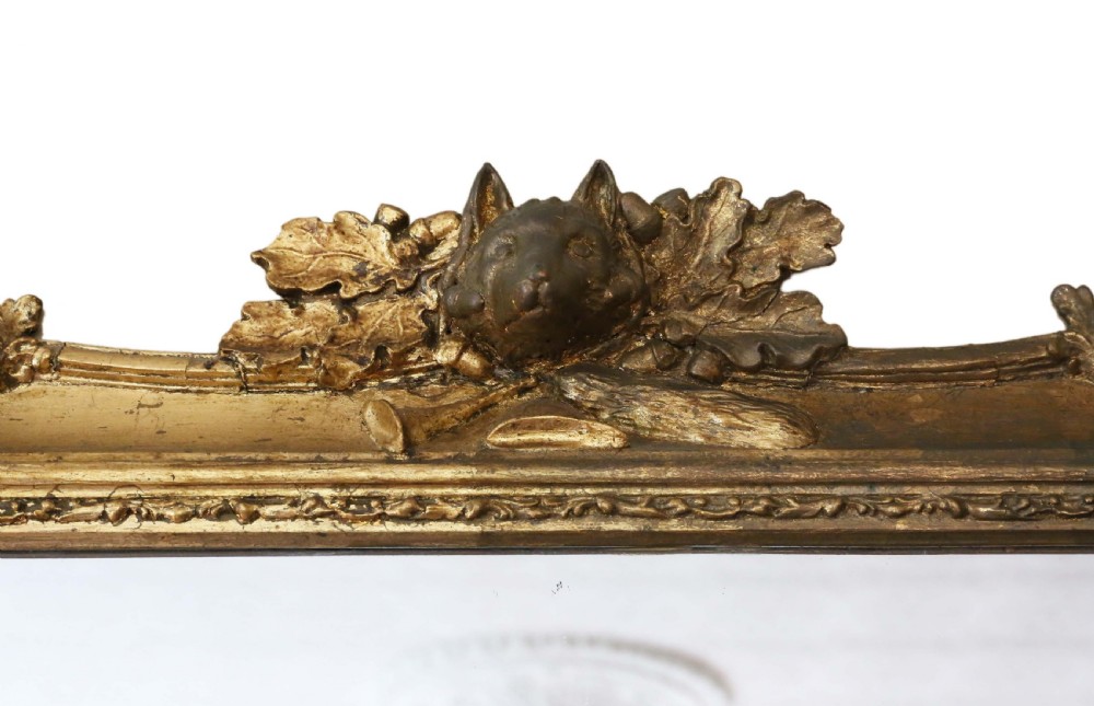 A 19th-century rectangular giltwood overmantle mirror featuring rococo scrollwork ornamentation and a central carved fox head crest at the top. View II