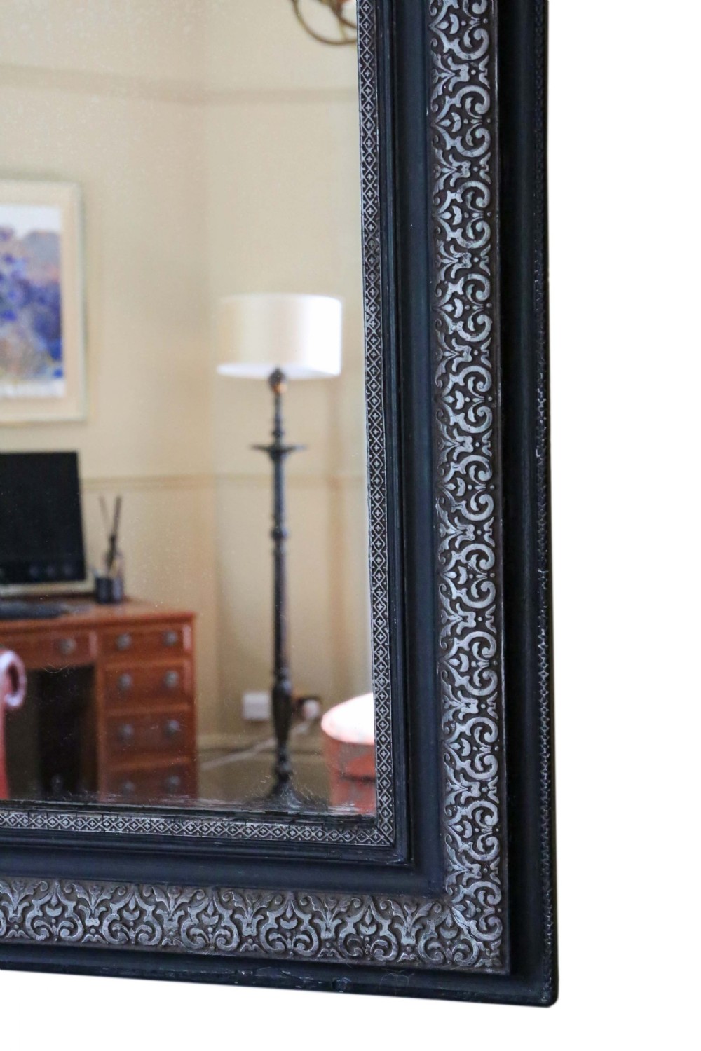 A large late 19th-century rectangular wall mirror featuring rounded top corners, an ebonised outer frame, and an embossed silver gilt inner border. View VI