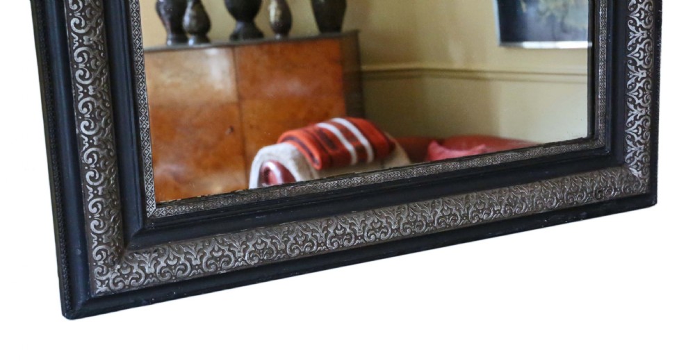 A large late 19th-century rectangular wall mirror featuring rounded top corners, an ebonised outer frame, and an embossed silver gilt inner border. View VII
