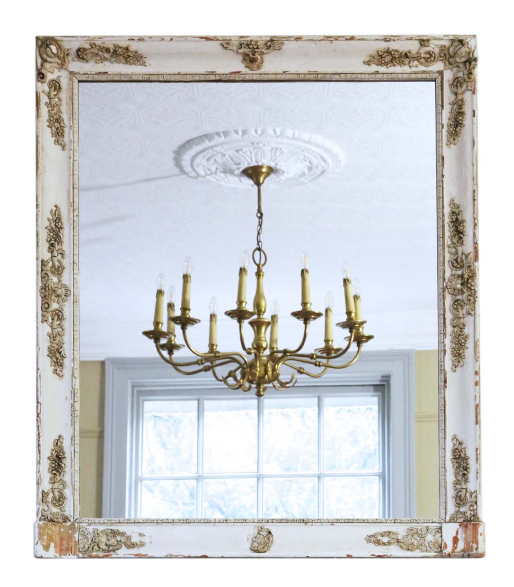 A large nineteenth-century rectangular French overmantle mirror with a cream-painted frame featuring moulded floral scrollwork details and a distressed finish.