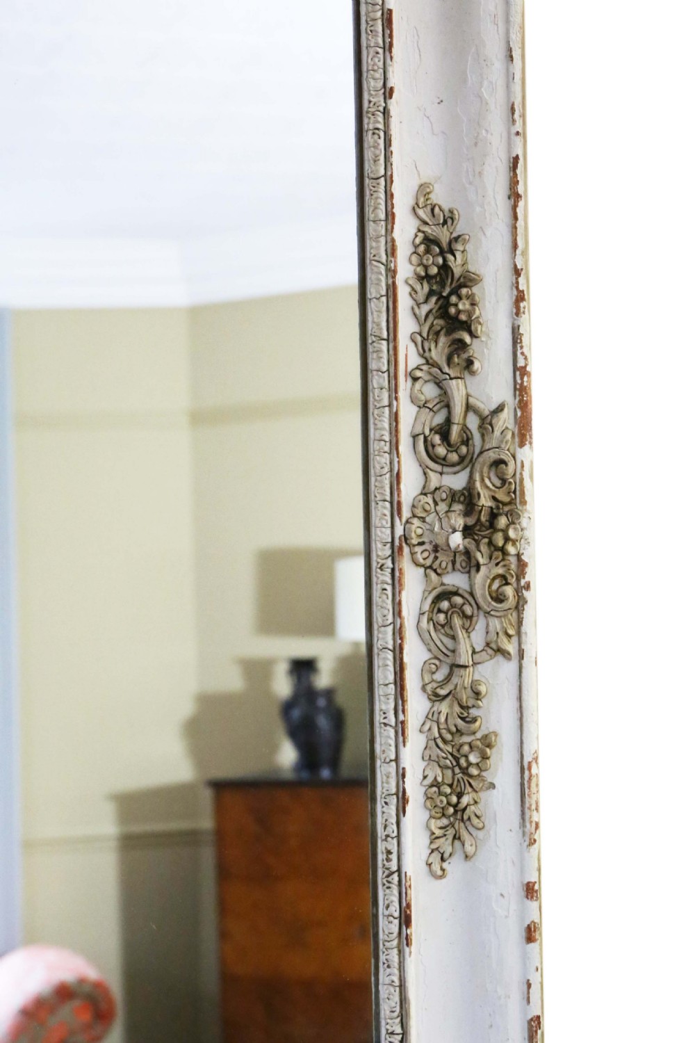 A large nineteenth-century rectangular French overmantle mirror with a cream-painted frame featuring moulded floral scrollwork details and a distressed finish. View III