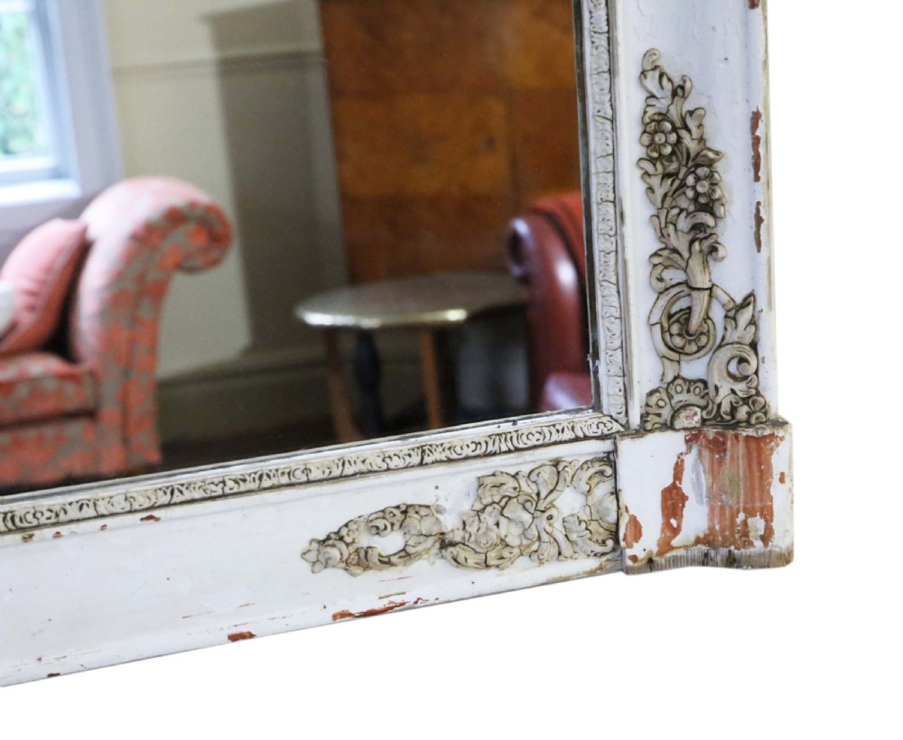 A large nineteenth-century rectangular French overmantle mirror with a cream-painted frame featuring moulded floral scrollwork details and a distressed finish. View VI