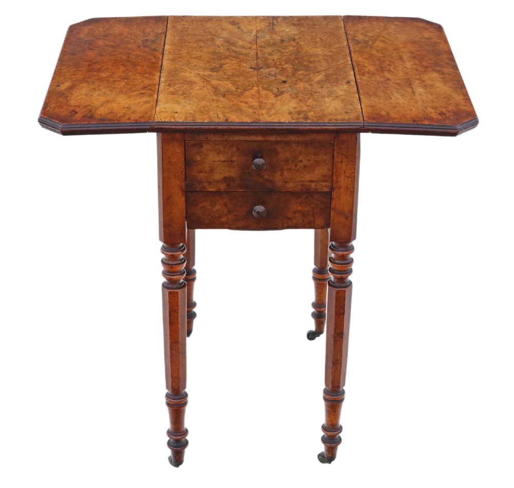A Victorian burr walnut drop-leaf work table featuring two drawers, turned legs, and brass castors against a plain background. View V