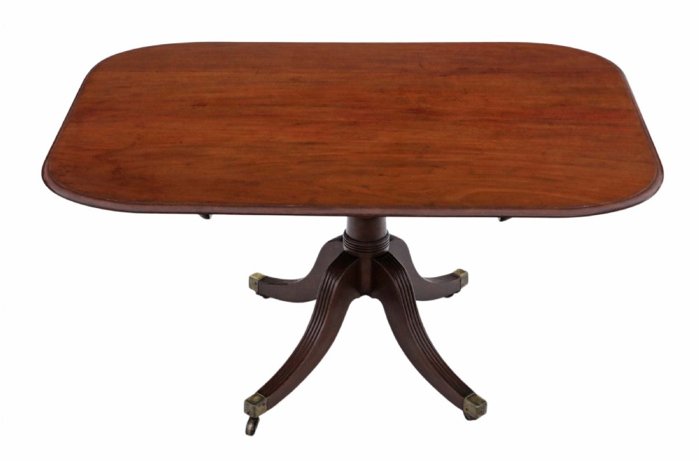 An early nineteenth-century Regency mahogany tilt-top table shown upright, featuring a rectangular top, central pedestal, reeded legs, and brass castors. View III