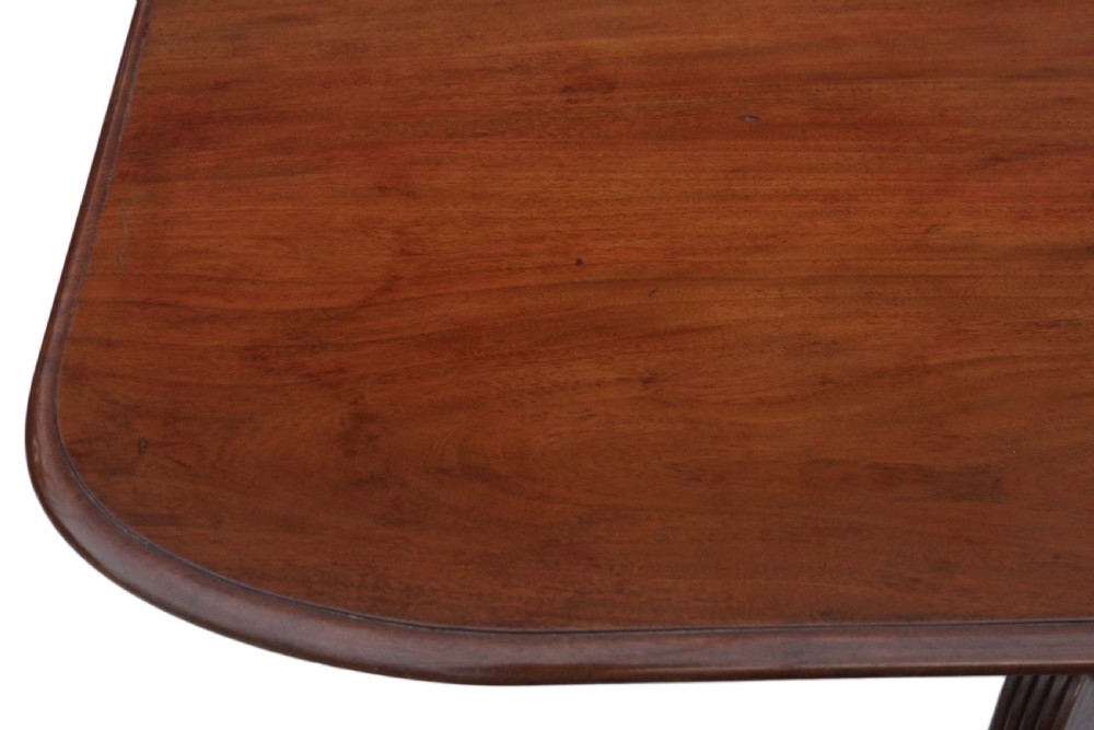 An early nineteenth-century Regency mahogany tilt-top table shown upright, featuring a rectangular top, central pedestal, reeded legs, and brass castors. View VIII