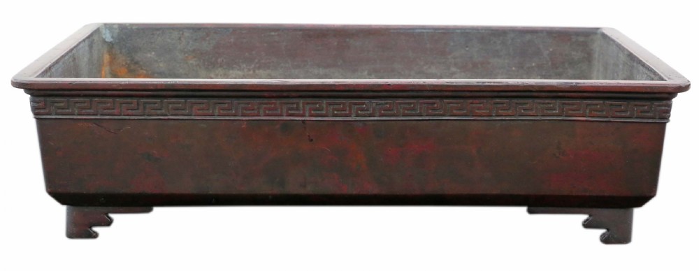 A rectangular dark bronze Japanese suiban planter featuring a key fret relief pattern around the upper border and four corner bracket feet.