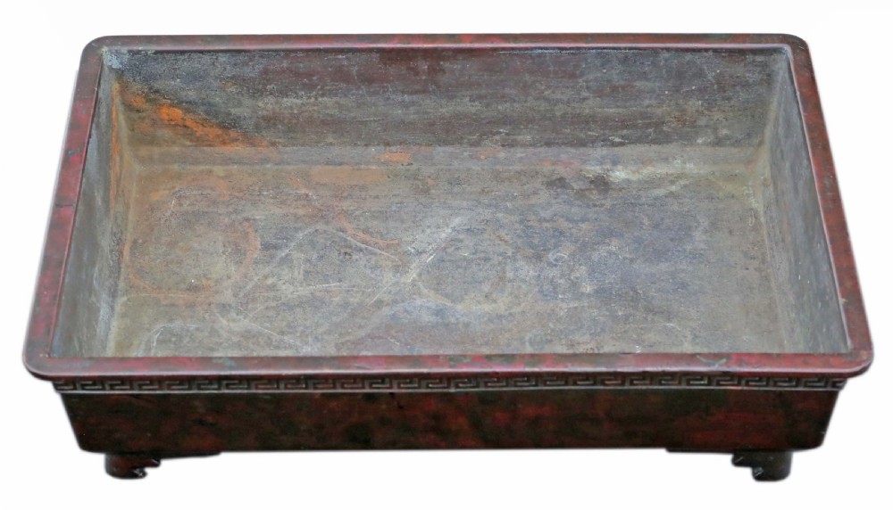 A rectangular dark bronze Japanese suiban planter featuring a key fret relief pattern around the upper border and four corner bracket feet. View V