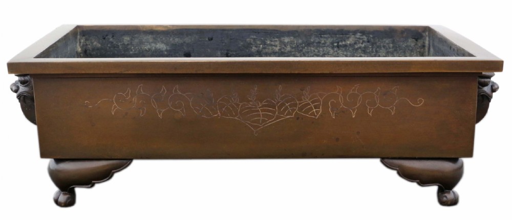 A rectangular Japanese bronze suiban planter featuring incised foliage motifs on the front panel and raised corner feet.