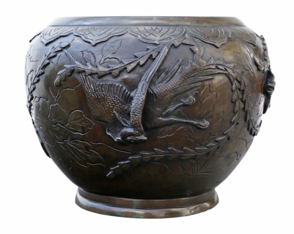 A bulbous dark bronze jardiniere decorated with high-relief carvings of birds among foliage and a stylized border around the rim.