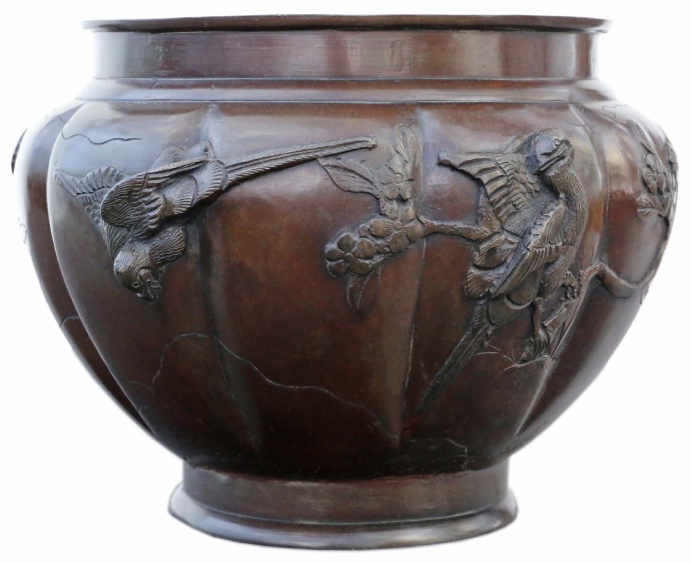 A large lobed dark bronze Japanese Meiji period jardiniere featuring raised high-relief carvings of birds perched on blossoming branches.