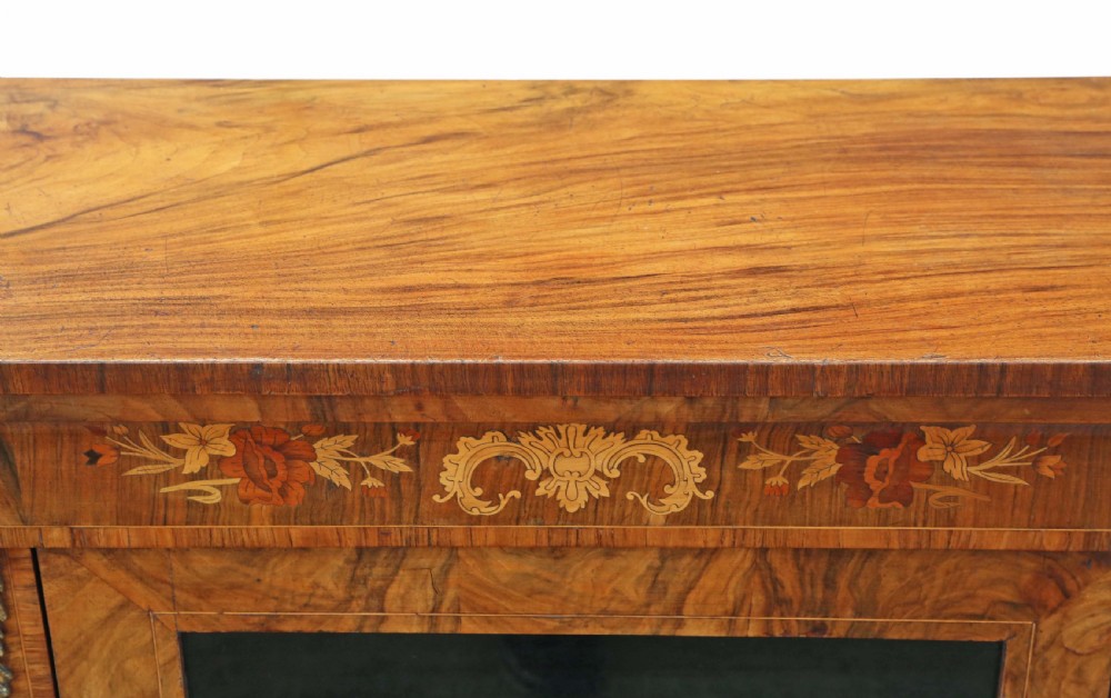 A Victorian burr walnut pier display cabinet featuring a single glazed door, floral marquetry inlay at the upper frieze, and brass mounts on the sides. View VIII