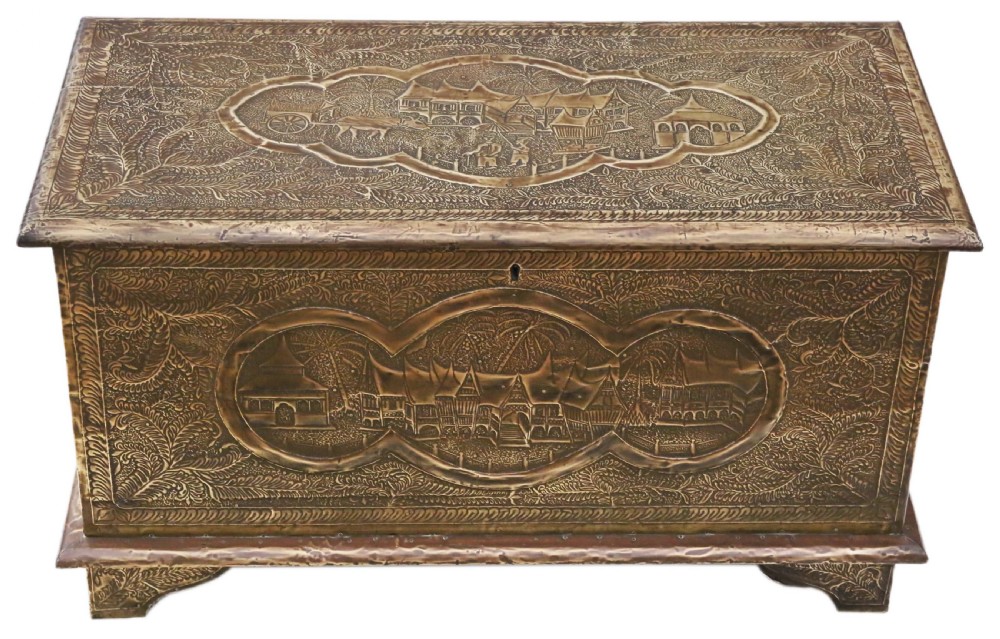 A rectangular wooden storage chest fully encased in hand-embossed brass sheeting featuring Chinoiserie landscape scenes and foliate borders.
