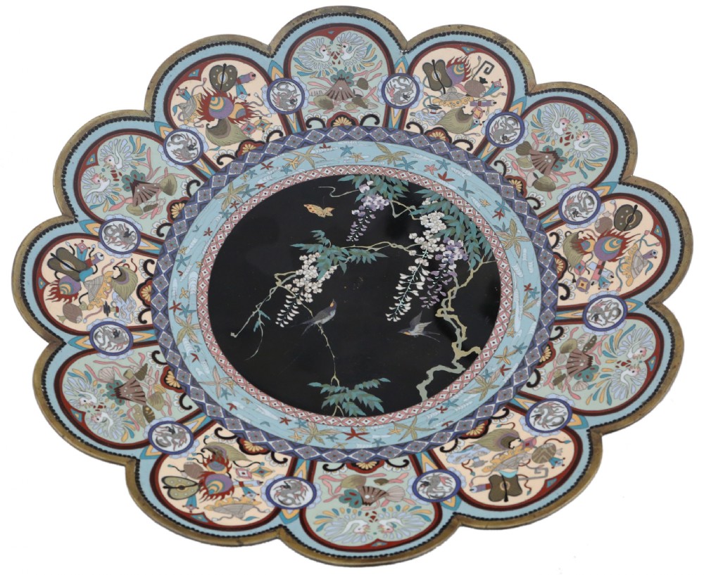 A large Japanese Meiji period scalloped cloisonne charger plate featuring a black central panel decorated with wisteria and birds, framed by intricate polychrome enamel outer borders. View V