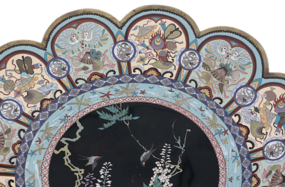A large Japanese Meiji period scalloped cloisonne charger plate featuring a black central panel decorated with wisteria and birds, framed by intricate polychrome enamel outer borders. View IX