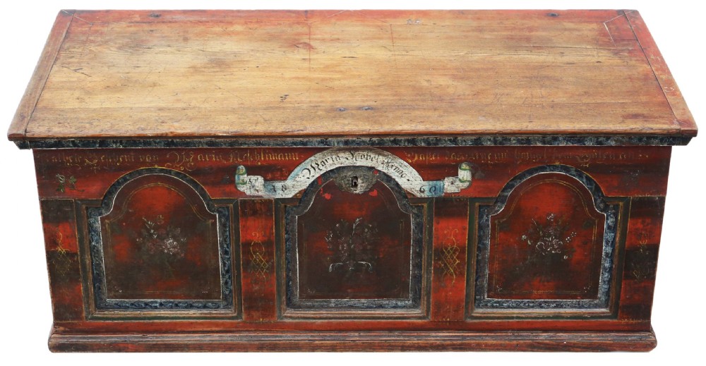 An antique rectangular wooden coffer with a natural pine lid and a red and dark green painted front featuring three arched panels with floral motifs.