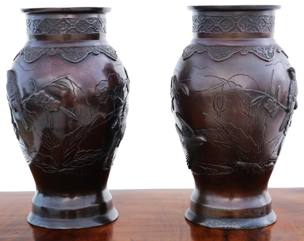 A pair of dark brown patinated Japanese Meiji period bronze vases featuring high relief carvings of birds perched on branches with geometric borders. View VI