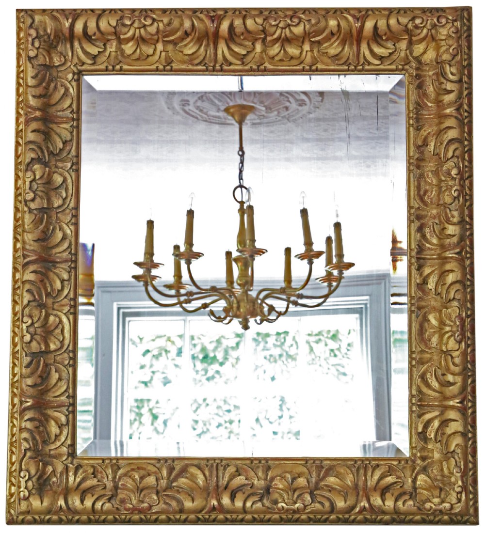 A rectangular gilded wall mirror featuring a carved leaf motif border with bevelled edge mirror glass.
