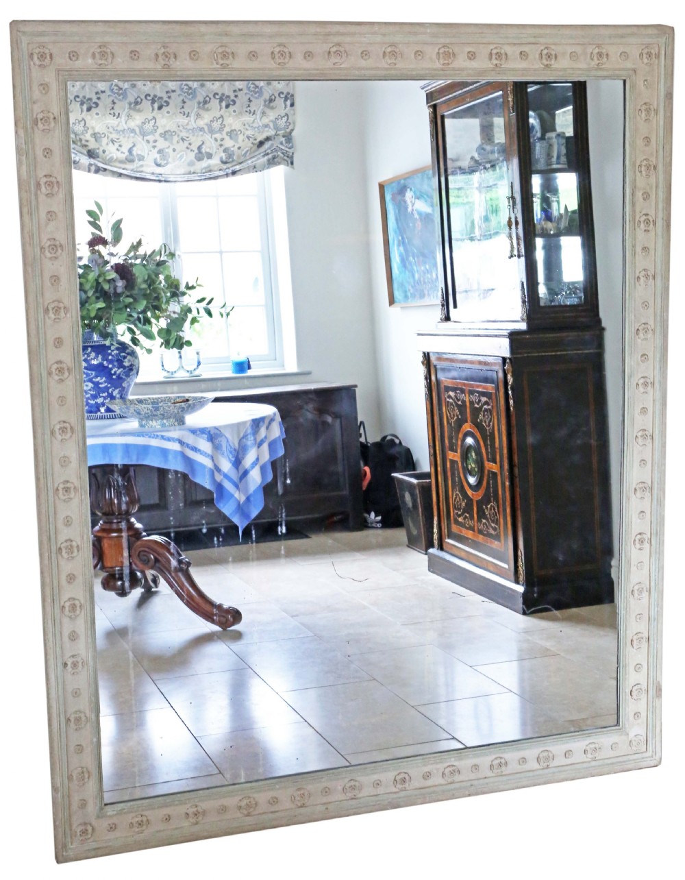 A large rectangular wall mirror featuring a pale off-white painted wooden frame decorated with carved rosettes along the border.