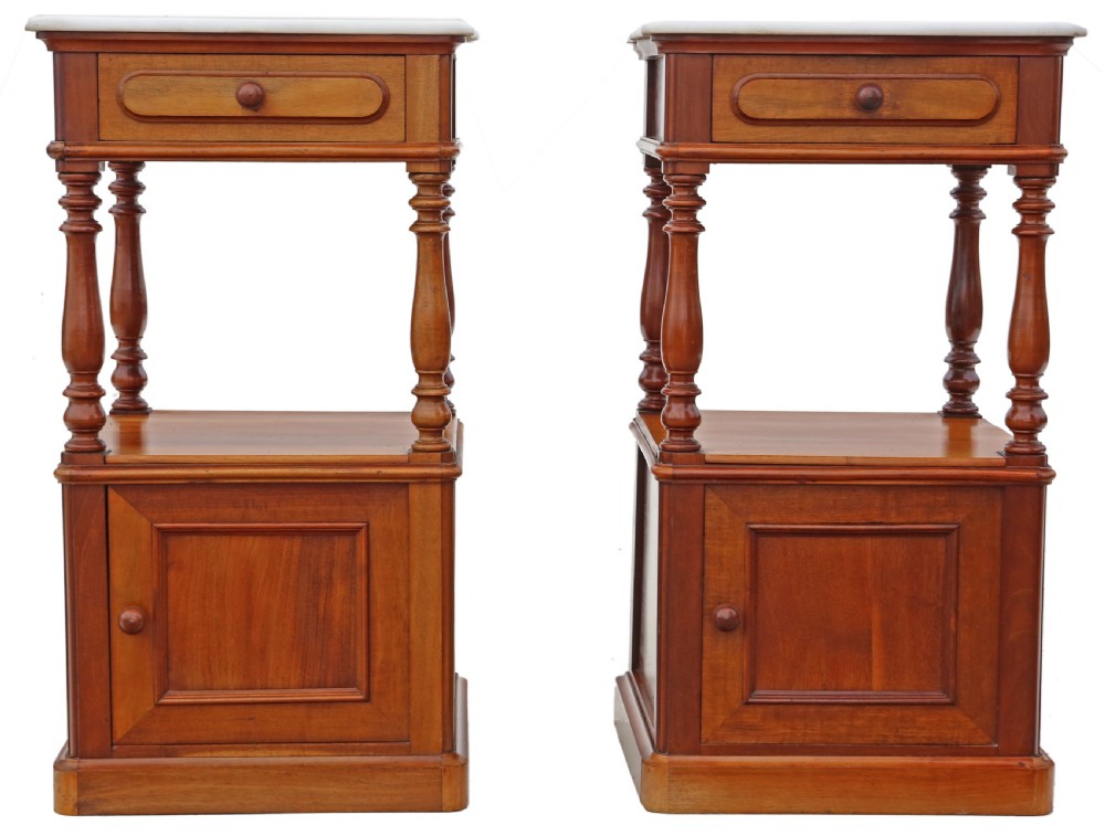 A pair of French walnut bedside tables featuring white marble tops, single upper drawers, open central shelves supported by turned columns, and lower single-door cupboards.
