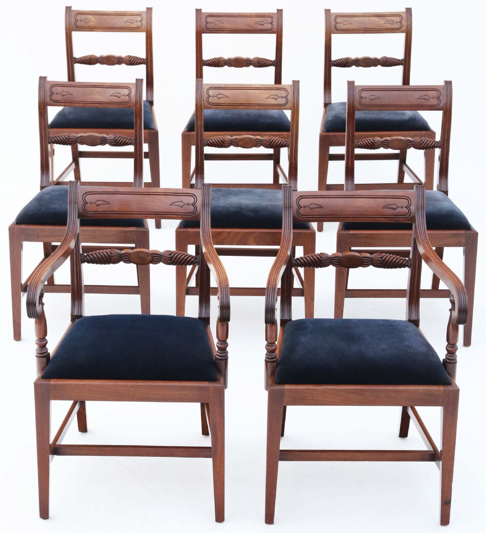 A set of eight Regency mahogany dining chairs featuring six single chairs and two carvers with dark blue velvet upholstered seats.