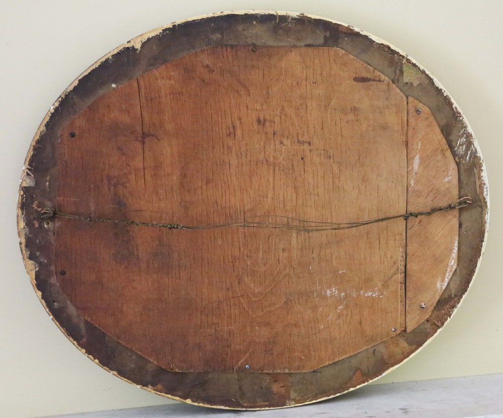 An oval 19th-century wall mirror featuring a carved outer gilt border surrounding a broad cream-painted inner frame. View III