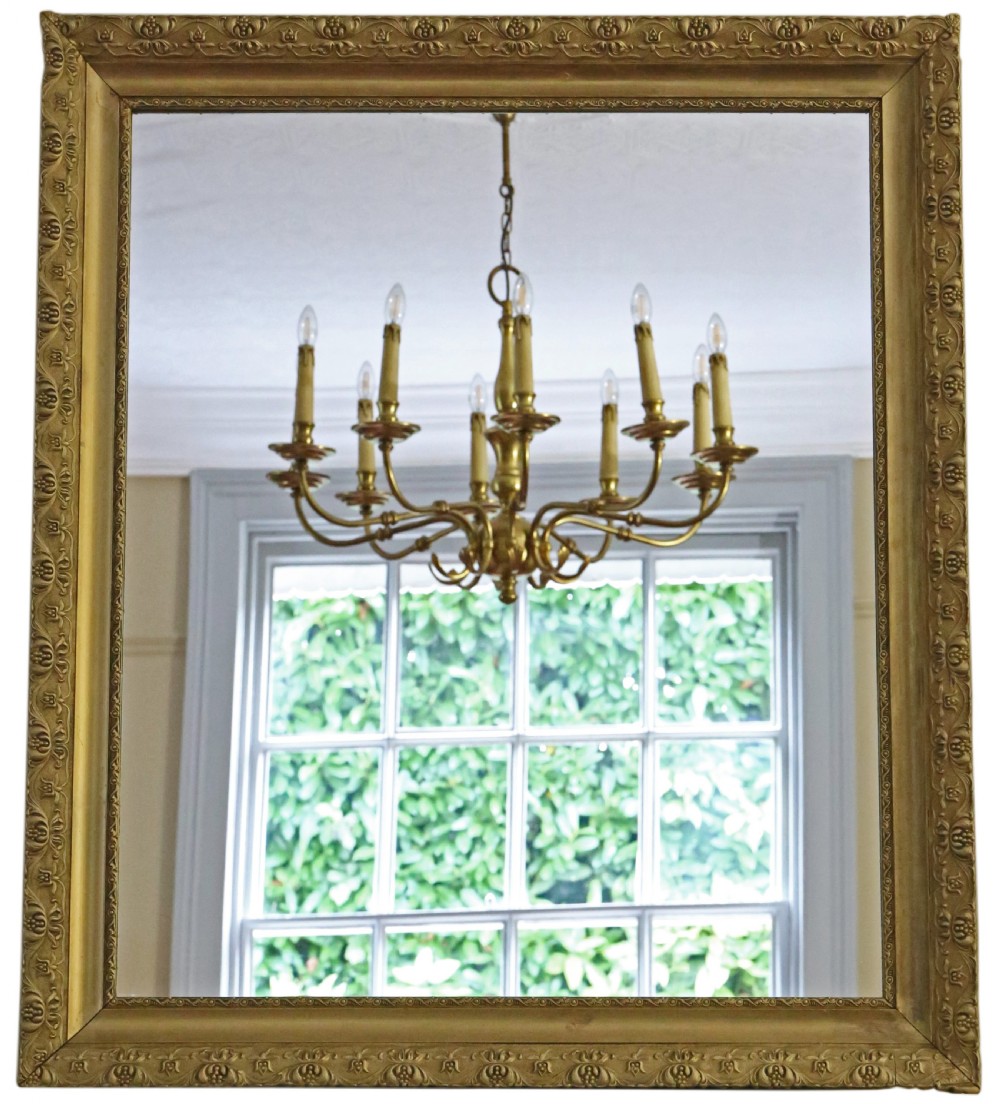 A large rectangular antique gilt overmantel mirror featuring detailed moulded borders and a gold finish.