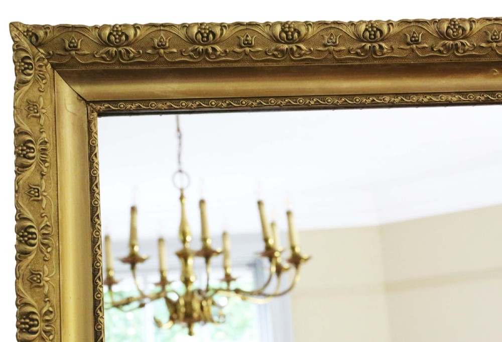 A large rectangular antique gilt overmantel mirror featuring detailed moulded borders and a gold finish. View II