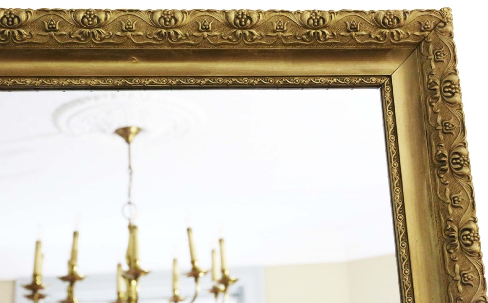 A large rectangular antique gilt overmantel mirror featuring detailed moulded borders and a gold finish. View III