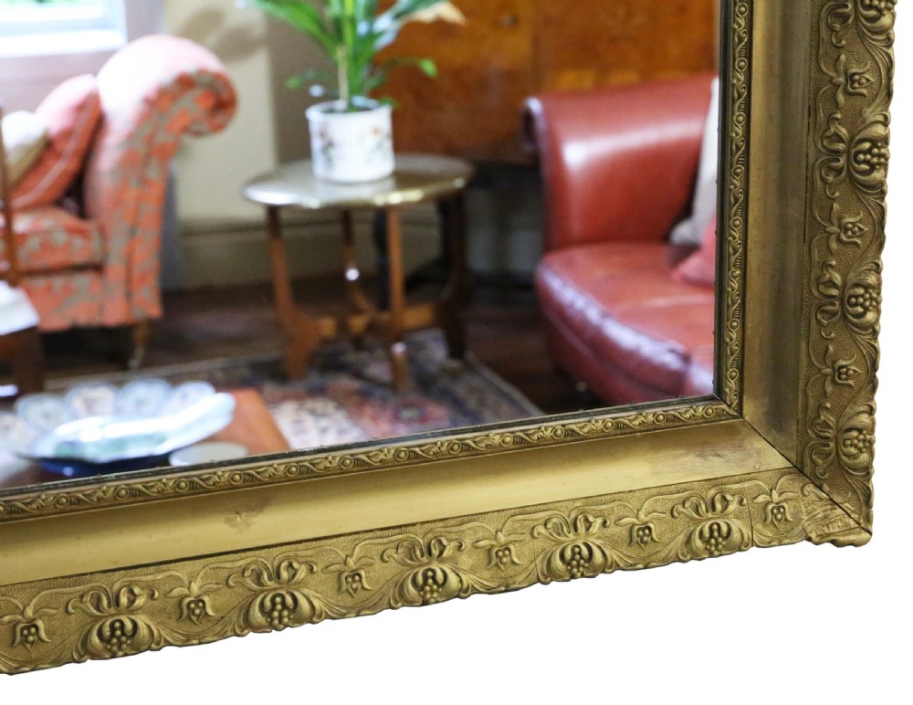 A large rectangular antique gilt overmantel mirror featuring detailed moulded borders and a gold finish. View IV