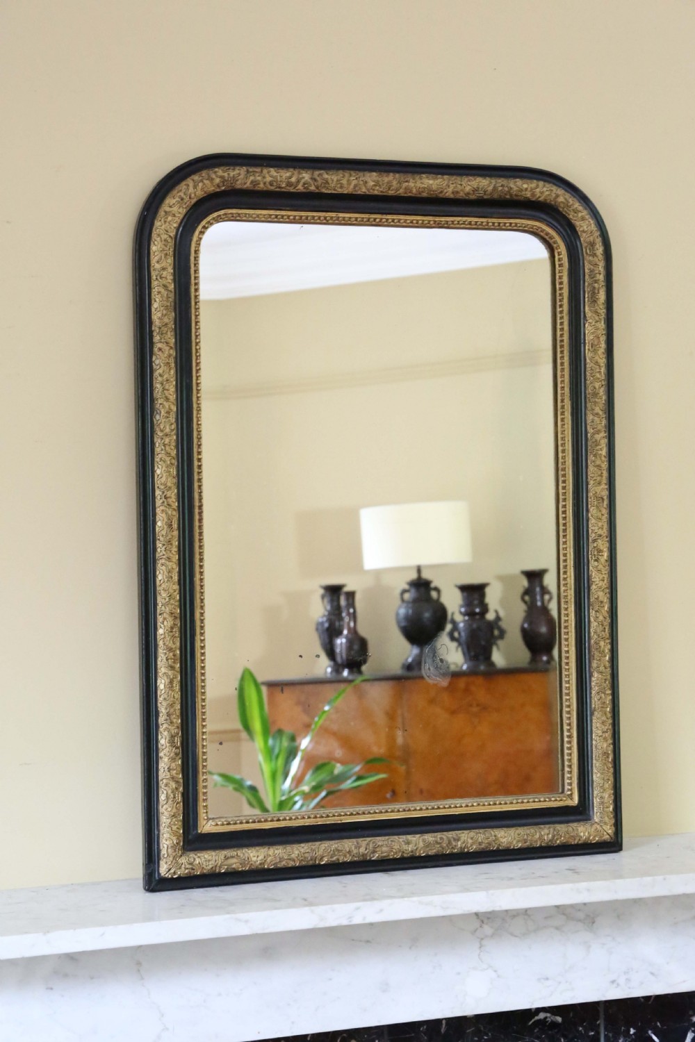 A nineteenth-century rectangular overmantel mirror with rounded top corners, featuring a dark ebonised frame bordered by ornate gilt mouldings. View VI