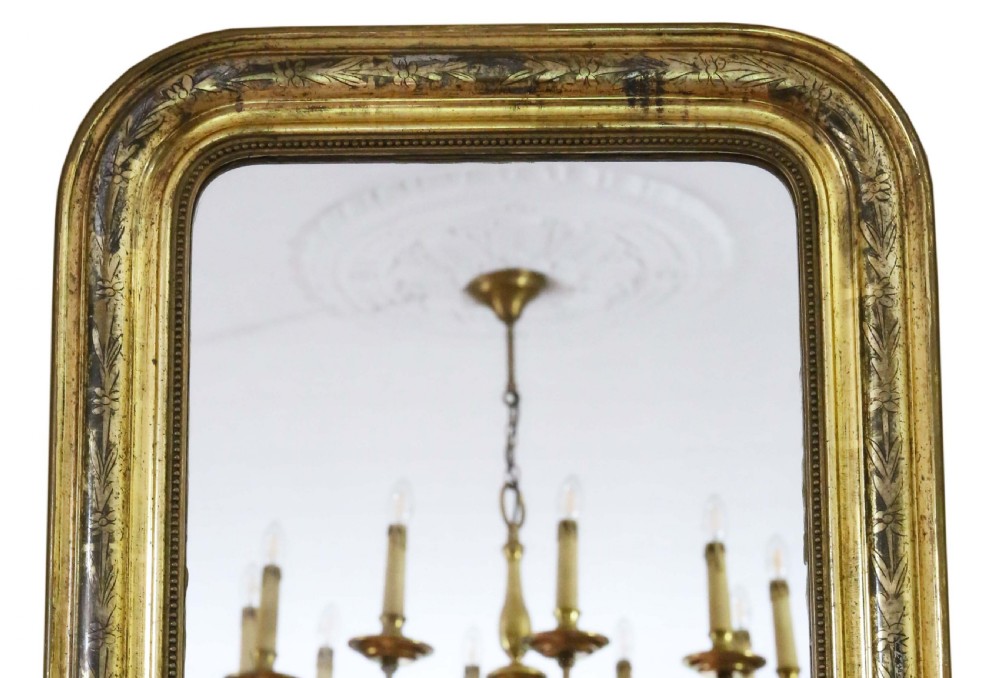 A nineteenth-century French Louis Philippe overmantel wall mirror featuring a gilt frame with rounded upper corners, engraved foliage motifs, and a beaded inner moulding. View II