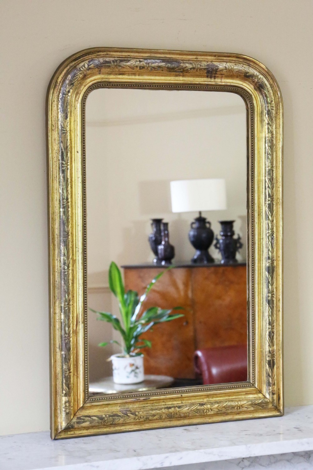A nineteenth-century French Louis Philippe overmantel wall mirror featuring a gilt frame with rounded upper corners, engraved foliage motifs, and a beaded inner moulding. View IV