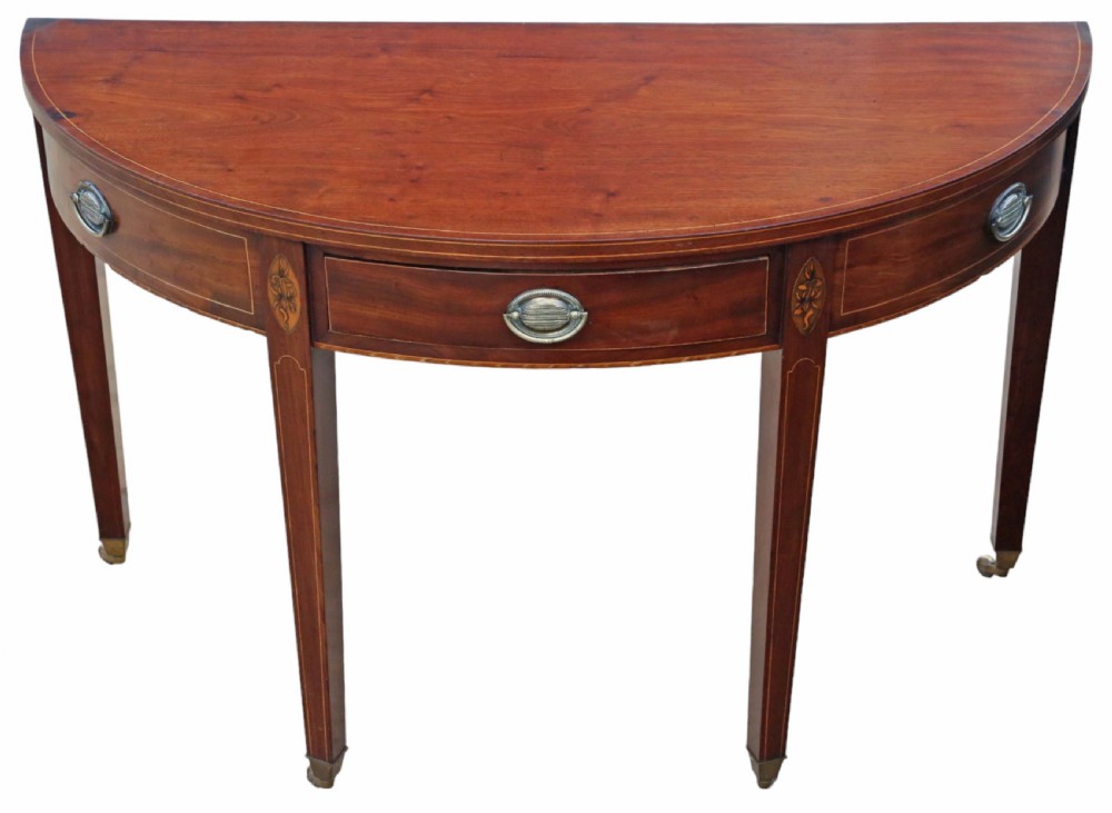 An early nineteenth-century semi-circular mahogany console table featuring line inlay, central drawers with brass ring handles, floral urn marquetry, and square tapered legs on brass castors.