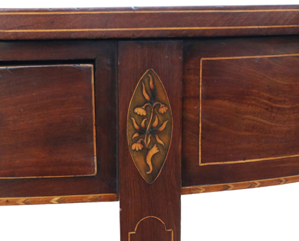 An early nineteenth-century semi-circular mahogany console table featuring line inlay, central drawers with brass ring handles, floral urn marquetry, and square tapered legs on brass castors. View V