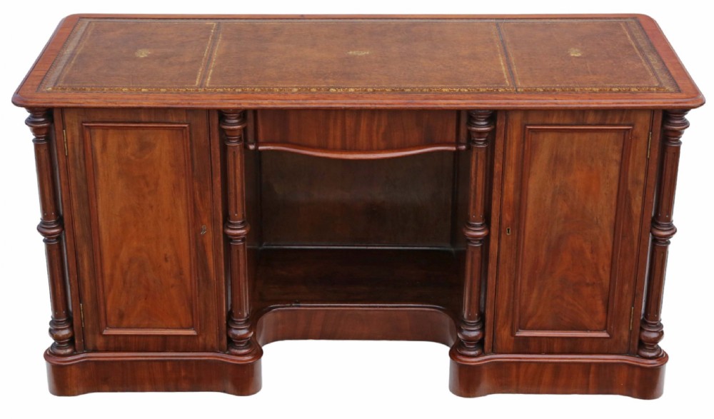 A 19th-century mahogany twin pedestal writing desk featuring a gold-tooled leather inset top, twin cupboard doors flanked by turned columns, and a central kneehole.
