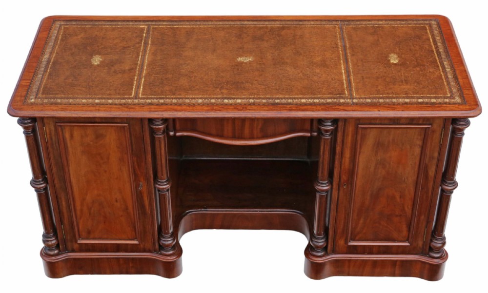 A 19th-century mahogany twin pedestal writing desk featuring a gold-tooled leather inset top, twin cupboard doors flanked by turned columns, and a central kneehole. View III