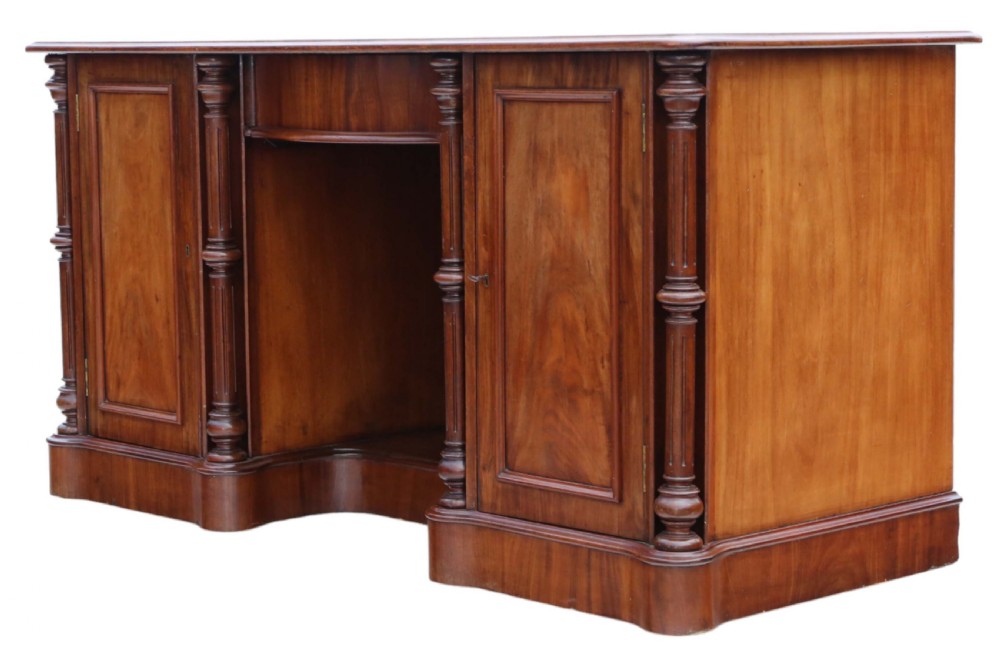 A 19th-century mahogany twin pedestal writing desk featuring a gold-tooled leather inset top, twin cupboard doors flanked by turned columns, and a central kneehole. View VII