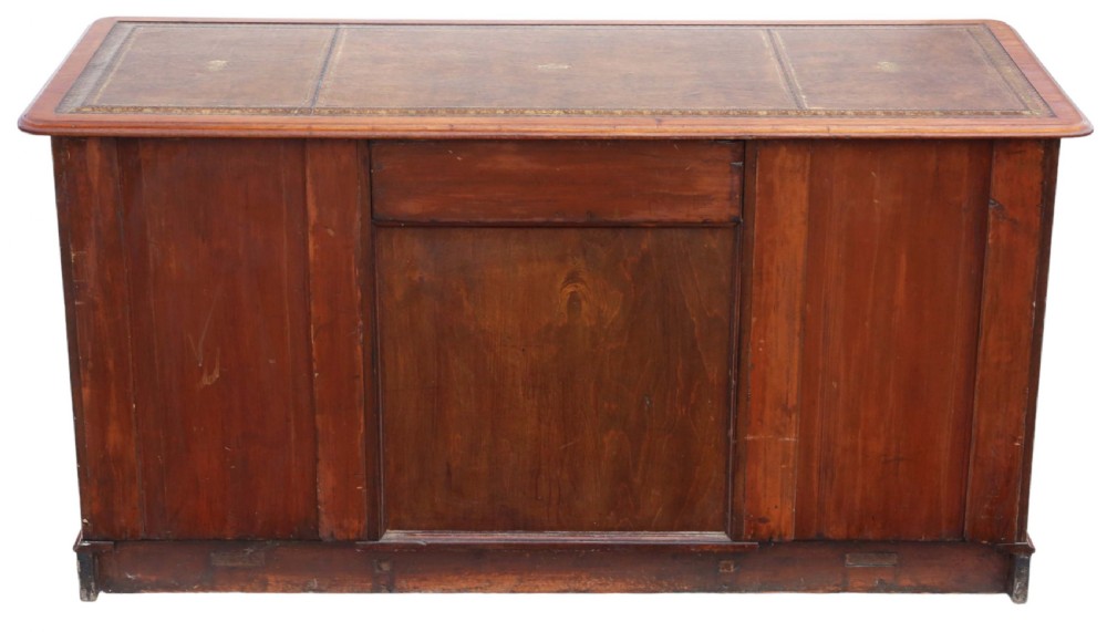 A 19th-century mahogany twin pedestal writing desk featuring a gold-tooled leather inset top, twin cupboard doors flanked by turned columns, and a central kneehole. View X