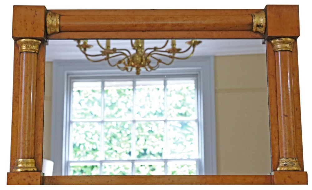 A 19th-century rectangular overmantel wall mirror featuring a birds eye maple veneer frame flanked by half-columns with giltwood capitals.