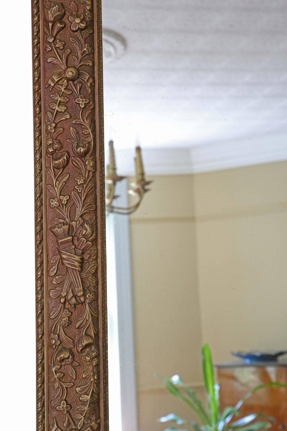 A large rectangular antique giltwood overmantel wall mirror featuring floral swags and a ribbon crest motif. View IV