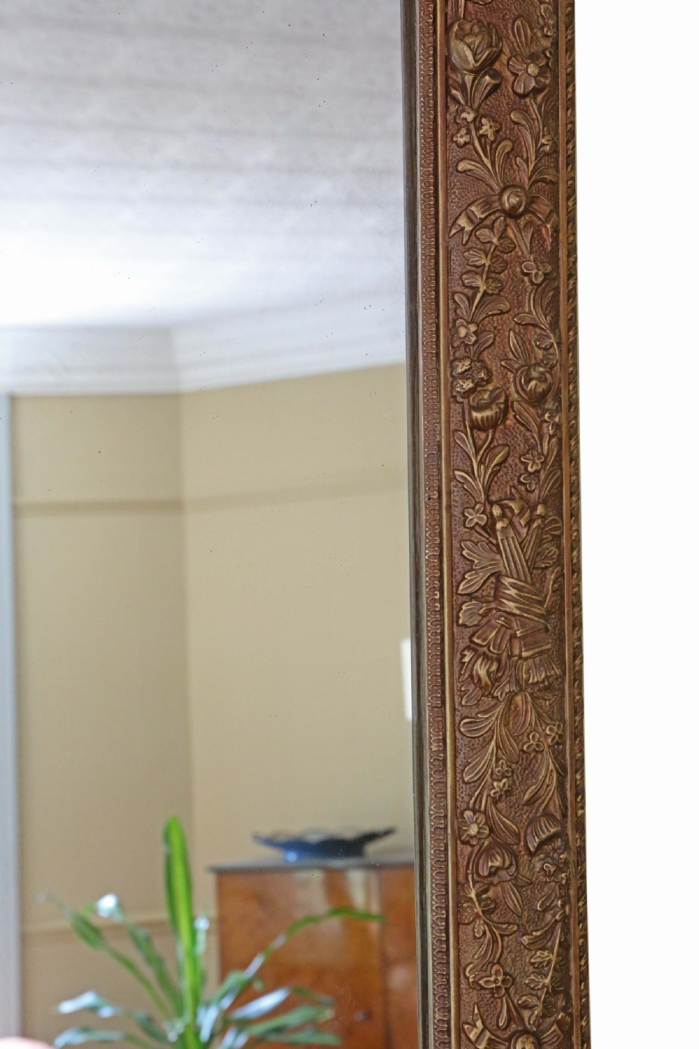 A large rectangular antique giltwood overmantel wall mirror featuring floral swags and a ribbon crest motif. View V