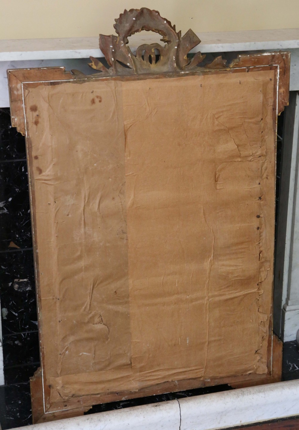 A large rectangular antique giltwood overmantel wall mirror featuring floral swags and a ribbon crest motif. View VI