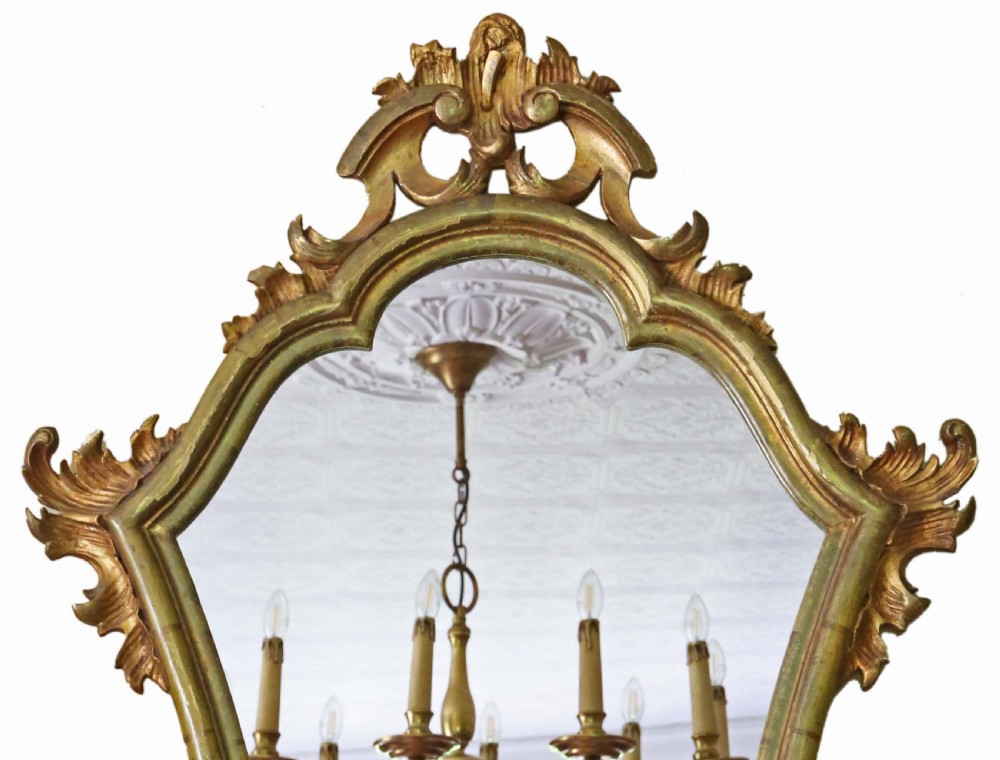 An ornate turn-of-the-century Rococo Revival overmantel mirror featuring a carved gilt wood frame with fluid scrollwork and foliage cresting. View II