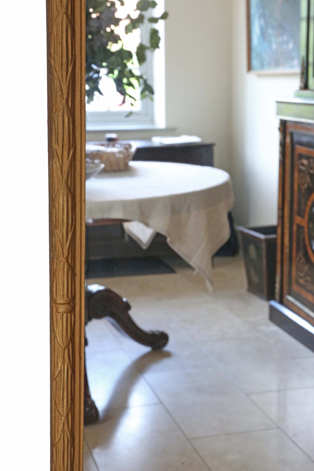 A tall rectangular full-length mirror featuring a gilded wood frame topped with a bow and ribbon cresting. View V