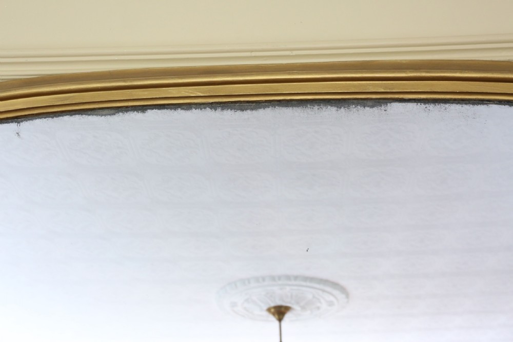 A large nineteenth-century arched giltwood overmantel mirror with subtle scroll mouldings along the lower frame. View V